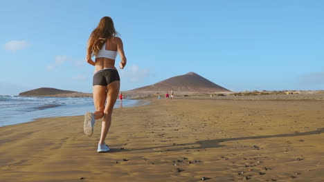 Silueta-De-Atleta-Mujer-Corriendo-En-La-Playa-Corriendo-Olas-Rompiendo-En-El-Fondo-De-La-Mañana-Junto-Al-Mar-Cámara-Lenta